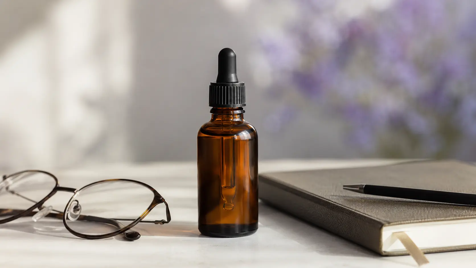 A single amber liquid-supplement dropper bottle on a clean, light surface beside a notebook and reading glasses, suggesting careful, evidence-minded consideration of what PolyMVA is.